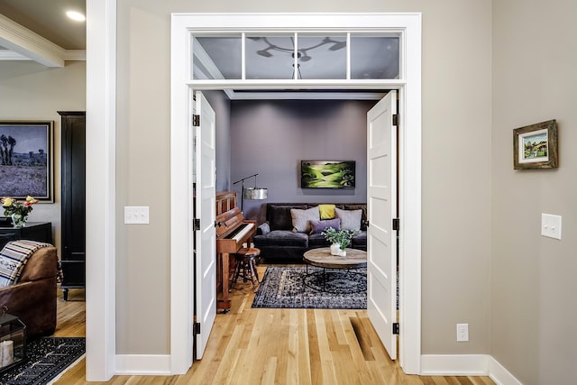 corridor featuring baseboards and light wood finished floors