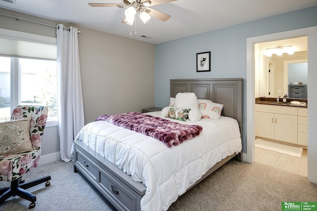 bedroom featuring visible vents, light carpet, and ensuite bathroom