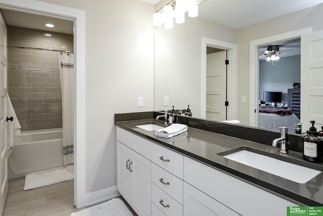 bathroom with double vanity, baseboards, a sink, and ensuite bath