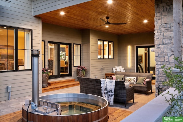 view of patio with a hot tub, a deck, outdoor lounge area, and a ceiling fan