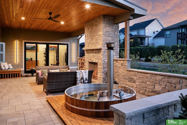 view of patio featuring ceiling fan, fence, and an outdoor living space with a fireplace
