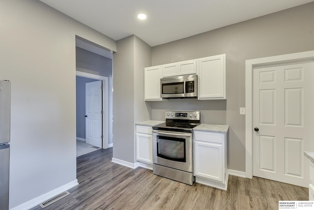 kitchen featuring visible vents, baseboards, white cabinets, light wood finished floors, and stainless steel appliances