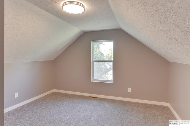 bonus room featuring carpet floors, vaulted ceiling, a textured ceiling, and visible vents