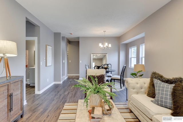 living room with an inviting chandelier, baseboards, and wood finished floors