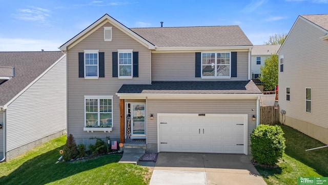 traditional-style house with a shingled roof, an attached garage, concrete driveway, and a front lawn
