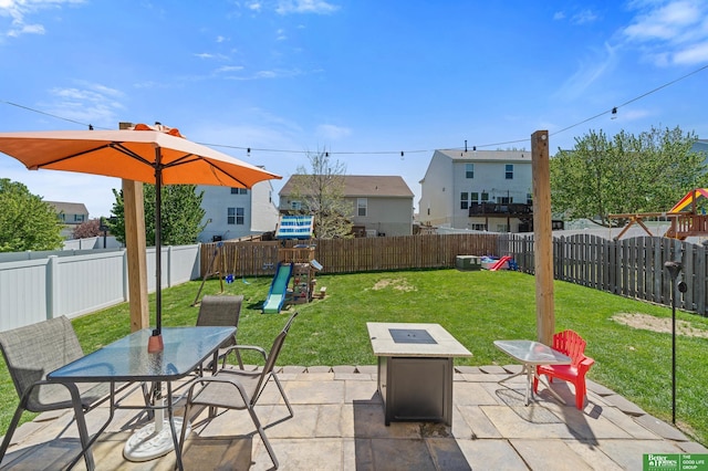view of patio / terrace featuring a fire pit, outdoor dining area, a fenced backyard, a playground, and a residential view