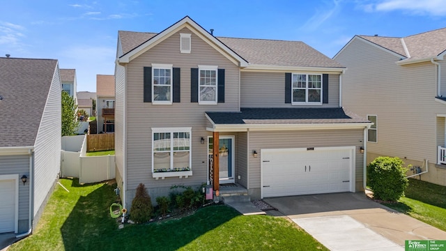traditional-style home with an attached garage, fence, a front yard, and concrete driveway