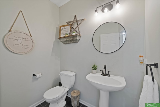 half bathroom with a sink, baseboards, tile patterned floors, and toilet