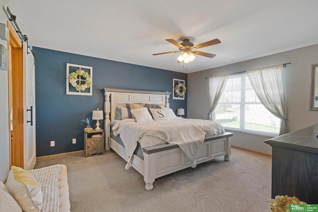 bedroom featuring baseboards, light colored carpet, a barn door, and ceiling fan