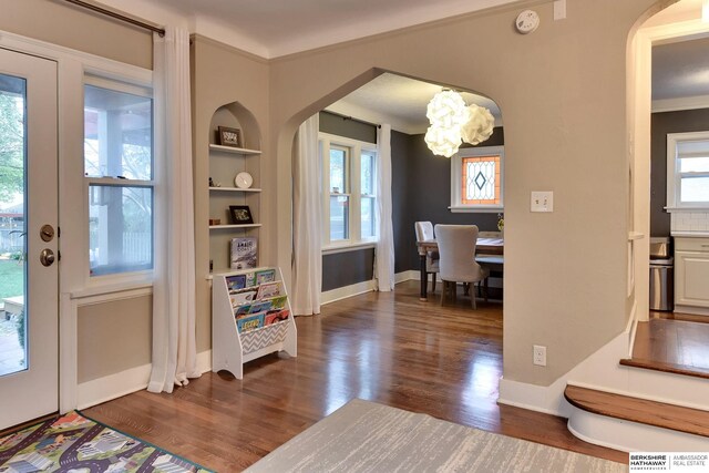 5117 Western Ave, Omaha, NE 68132 - entryway featuring arched walkways, dark wood-type flooring, a chandelier, crown molding, and baseboards