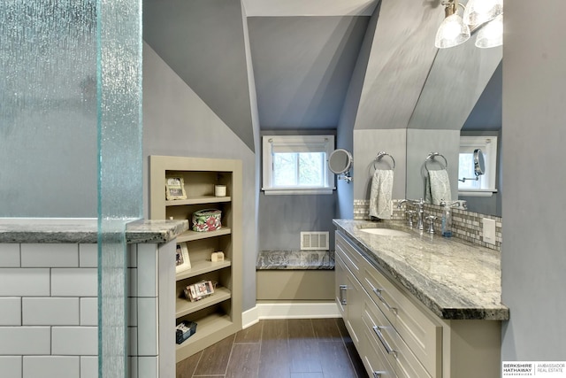 5117 Western Ave, Omaha, NE 68132 - bathroom featuring built in features, vanity, vaulted ceiling, baseboards, and tasteful backsplash