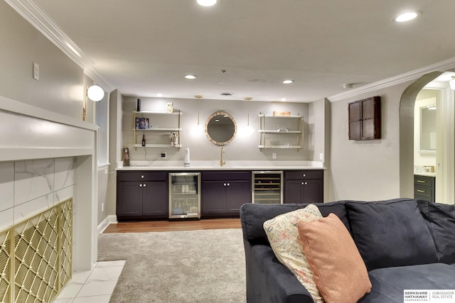 5117 Western Ave, Omaha, NE 68132 - indoor wet bar featuring wine cooler, crown molding, arched walkways, light wood finished floors, and recessed lighting