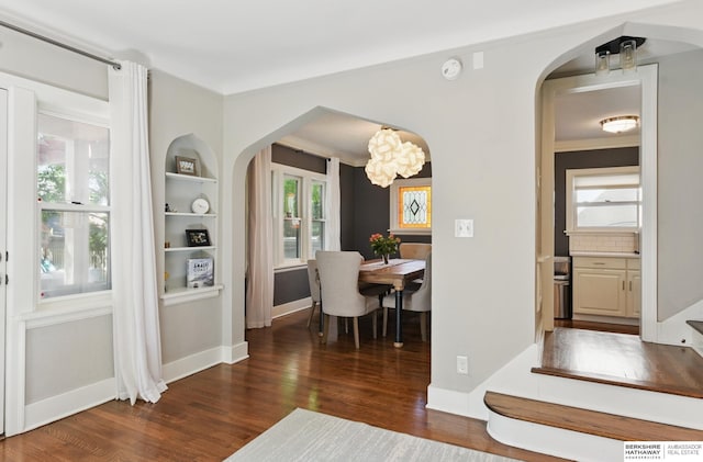 5117 Western Ave, Omaha, NE 68132 - dining room featuring arched walkways, wood finished floors, a chandelier, baseboards, and built in shelves