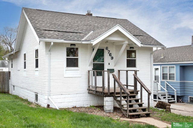 bungalow with a shingled roof and a chimney