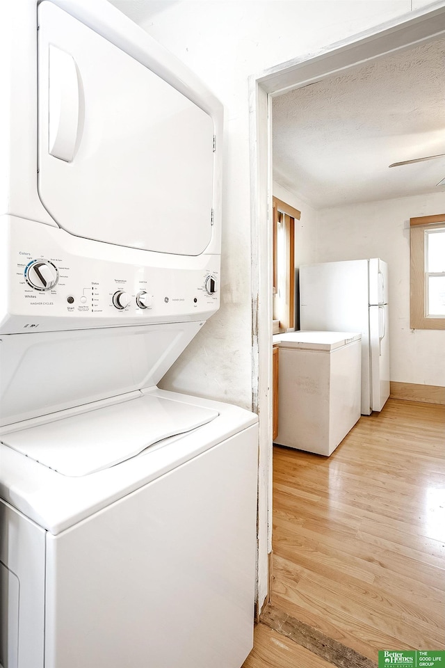 clothes washing area featuring light wood-style floors, laundry area, and stacked washer and dryer