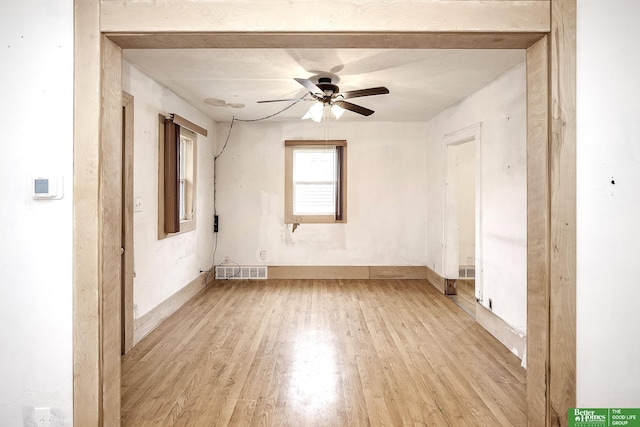 empty room featuring baseboards, a ceiling fan, light wood-style flooring, and visible vents