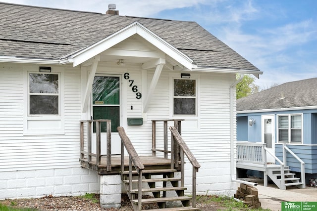 doorway to property with a shingled roof