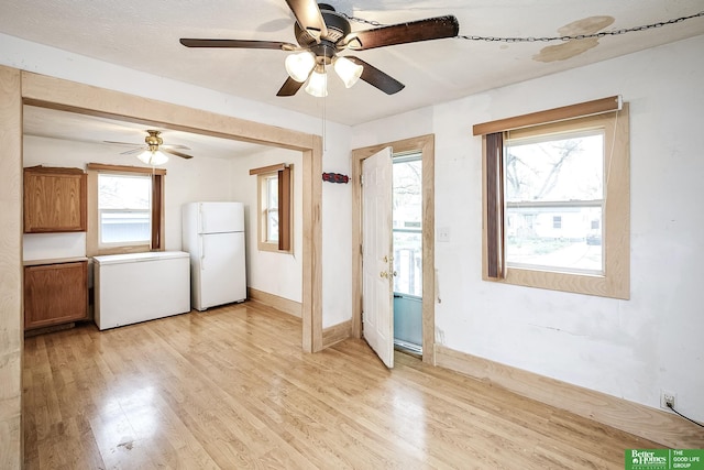 unfurnished room with light wood-style floors, ceiling fan, and a wealth of natural light