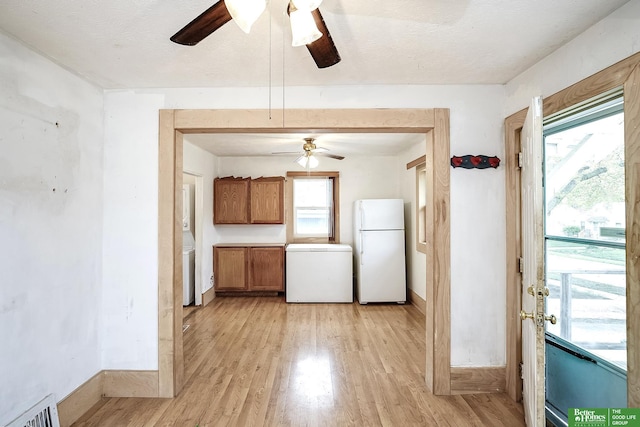 kitchen with ceiling fan, brown cabinetry, refrigerator, freestanding refrigerator, and light wood-style flooring