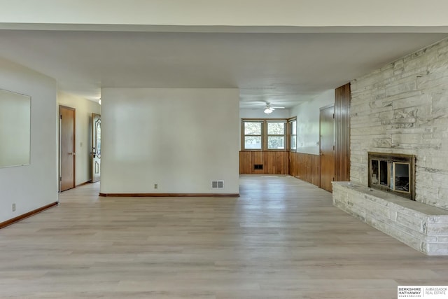 unfurnished living room with light wood-style floors, ceiling fan, a fireplace, and visible vents
