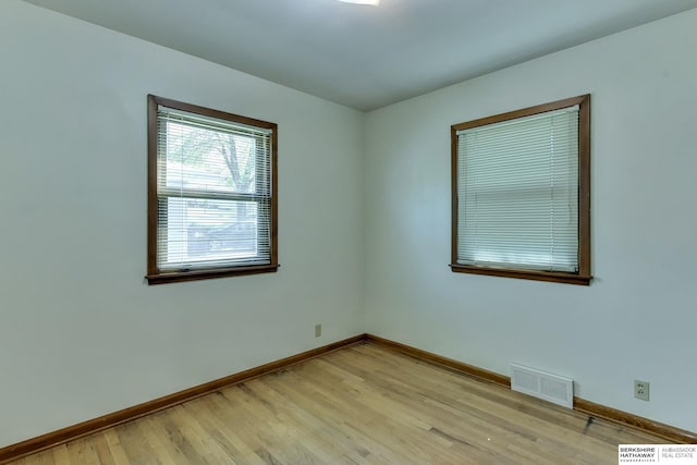 empty room with baseboards, visible vents, and light wood finished floors