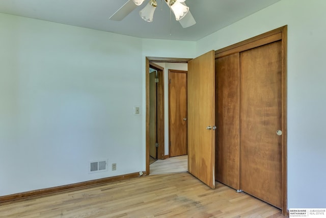 unfurnished bedroom featuring visible vents, a closet, baseboards, a ceiling fan, and light wood-style flooring