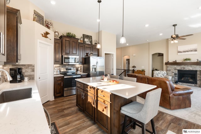 kitchen featuring ceiling fan, a breakfast bar, a sink, light countertops, and stainless steel appliances