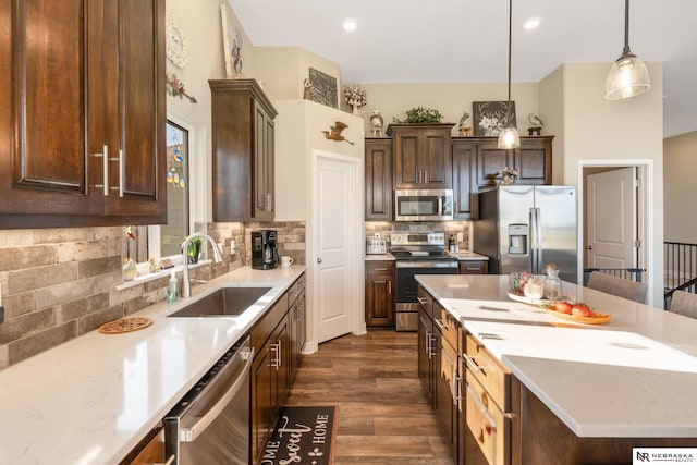 kitchen with dark wood-style flooring, a center island, tasteful backsplash, a sink, and stainless steel appliances