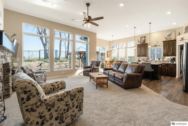 living room with recessed lighting, wood finished floors, ceiling fan with notable chandelier, and a fireplace