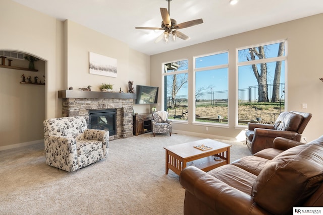 living room with carpet floors, a ceiling fan, baseboards, and a fireplace