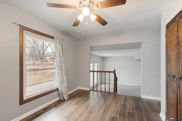 unfurnished room featuring baseboards, ceiling fan, wood finished floors, and visible vents