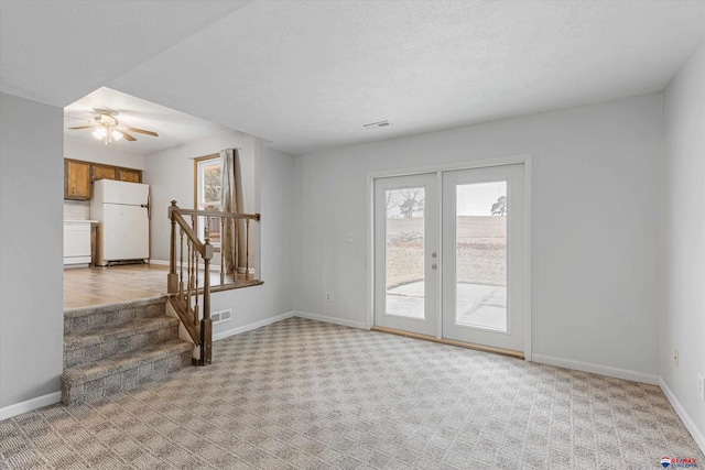 interior space with light colored carpet, a ceiling fan, baseboards, and visible vents