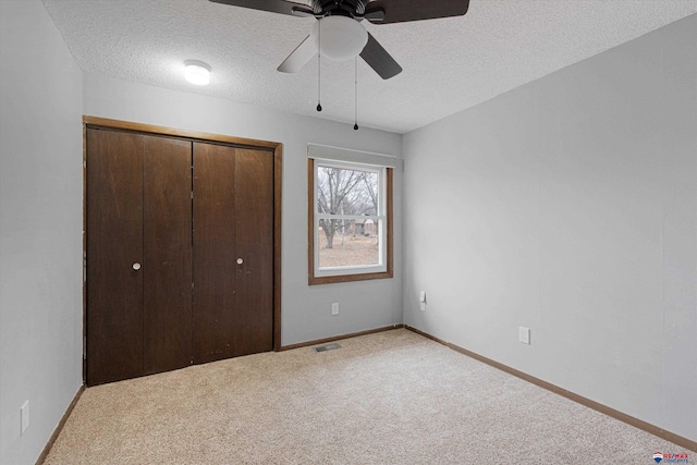 unfurnished bedroom featuring carpet floors, a textured ceiling, baseboards, visible vents, and a closet