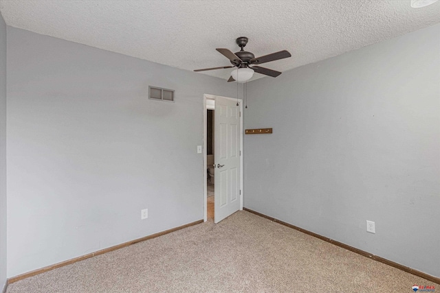 empty room with ceiling fan, light carpet, a textured ceiling, baseboards, and visible vents