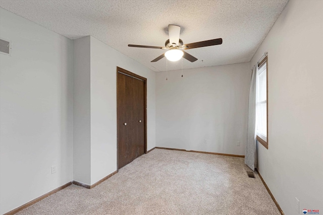 unfurnished room featuring a ceiling fan, a textured ceiling, visible vents, and light carpet