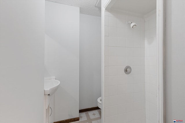 bathroom featuring toilet, a textured ceiling, and a tile shower