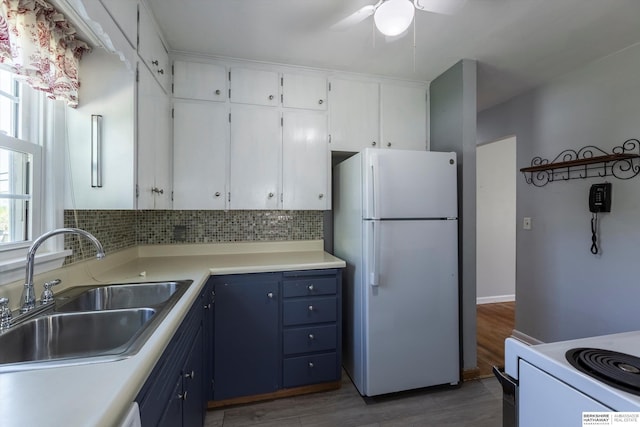 kitchen featuring white appliances, white cabinetry, a sink, and tasteful backsplash