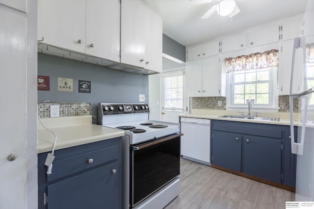kitchen with a sink, white appliances, light countertops, blue cabinetry, and backsplash