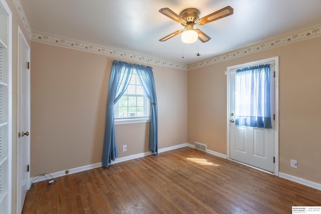 unfurnished room featuring baseboards, a ceiling fan, wood finished floors, and visible vents