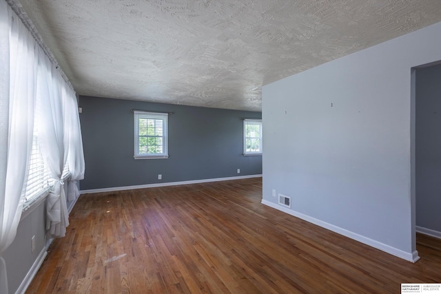 spare room with baseboards, visible vents, a healthy amount of sunlight, and wood finished floors