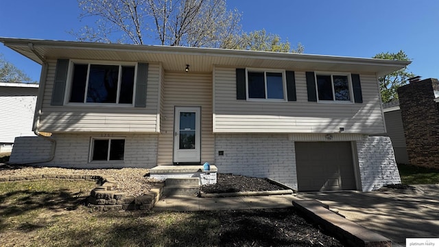 bi-level home featuring brick siding, a garage, and driveway