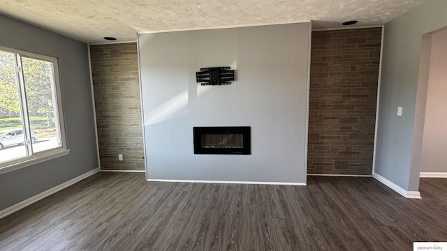 unfurnished living room with baseboards, a textured ceiling, and dark wood-style flooring