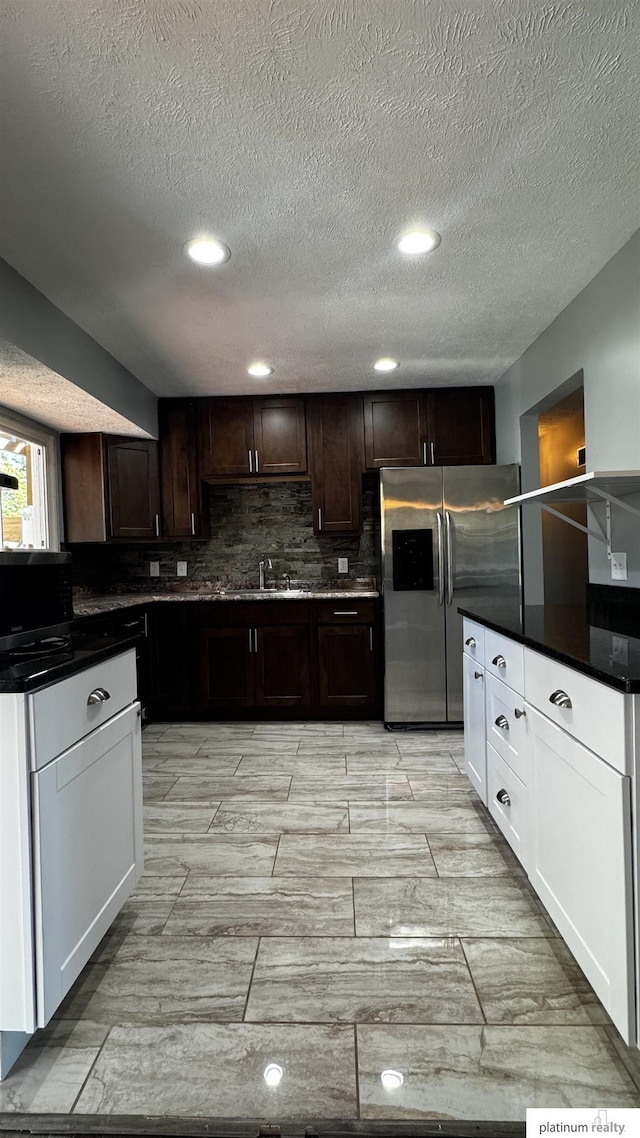 kitchen featuring decorative backsplash, dark brown cabinetry, a textured ceiling, dark countertops, and stainless steel appliances