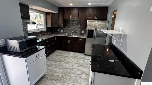 kitchen with appliances with stainless steel finishes, tasteful backsplash, dark brown cabinets, a sink, and marble finish floor