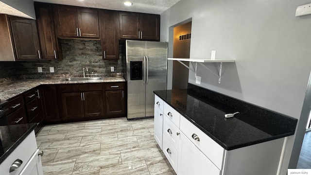 kitchen with white cabinets, dark brown cabinets, a sink, tasteful backsplash, and stainless steel refrigerator with ice dispenser
