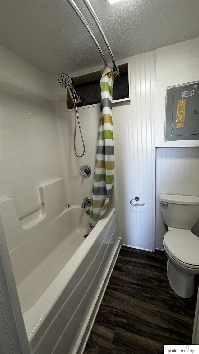 bathroom with a textured ceiling, electric panel, toilet, and wood finished floors