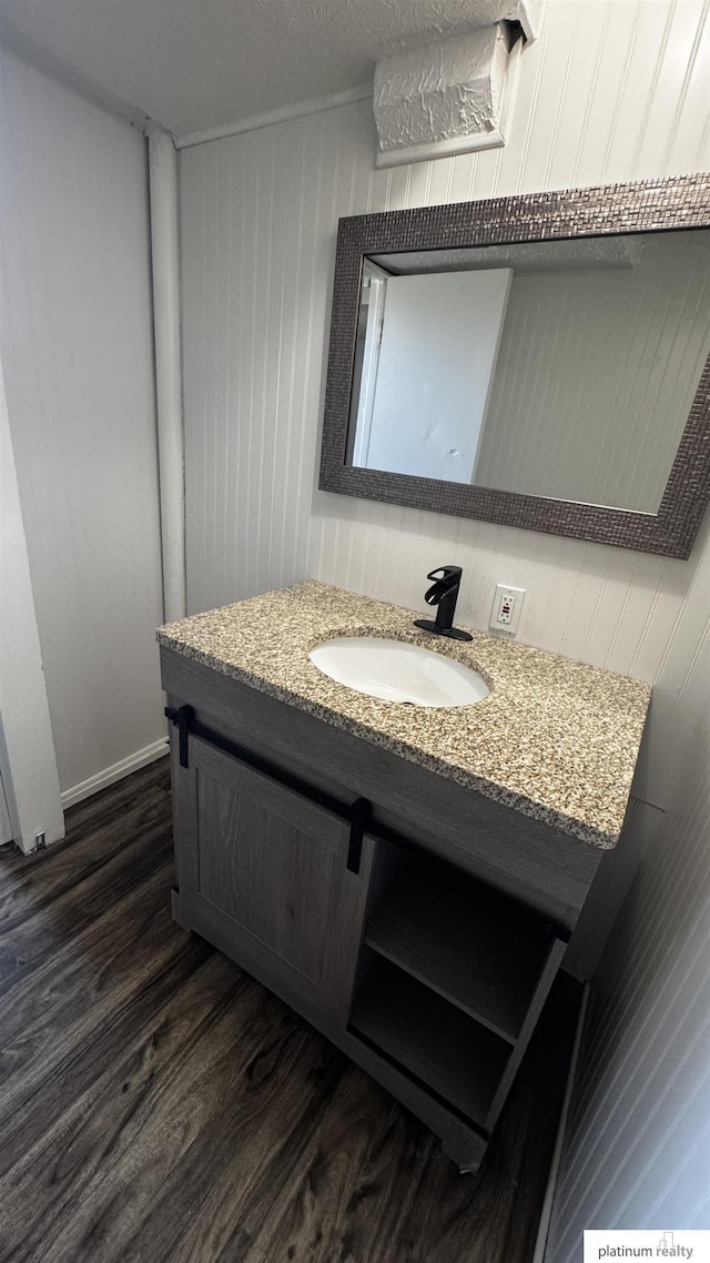 bathroom with vanity, wood walls, and wood finished floors