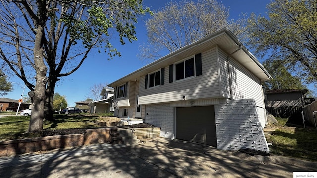 raised ranch with brick siding, a garage, fence, and driveway