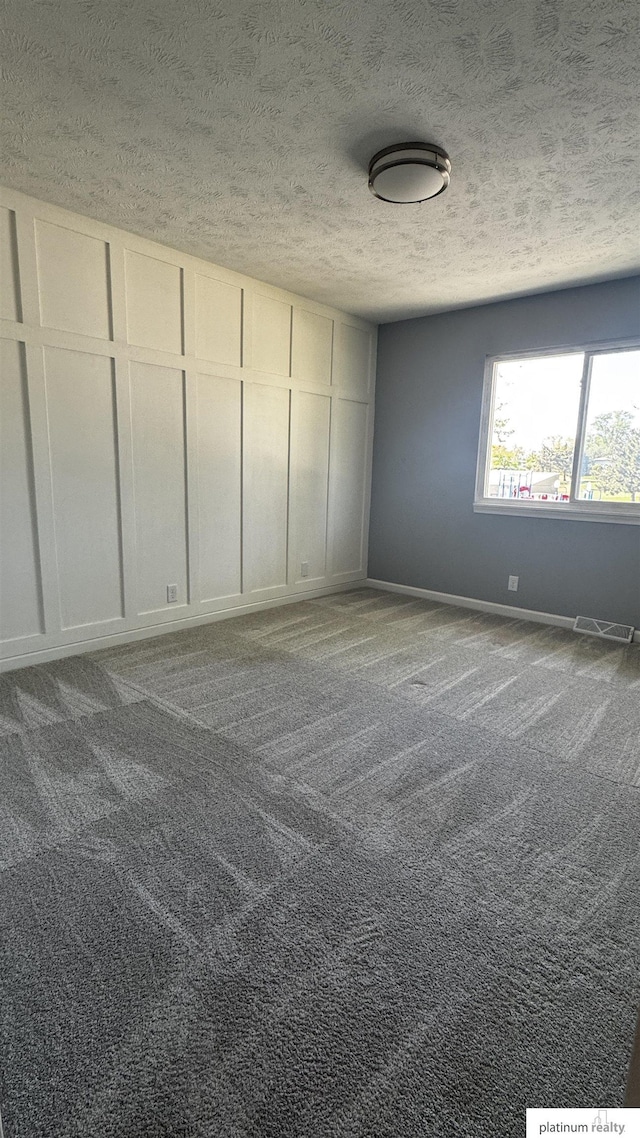 unfurnished bedroom featuring carpet flooring, a textured ceiling, visible vents, and baseboards