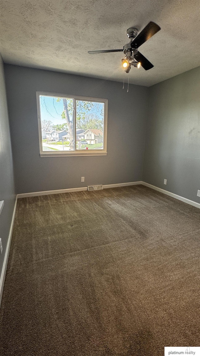 carpeted empty room featuring baseboards, a ceiling fan, a textured ceiling, and visible vents